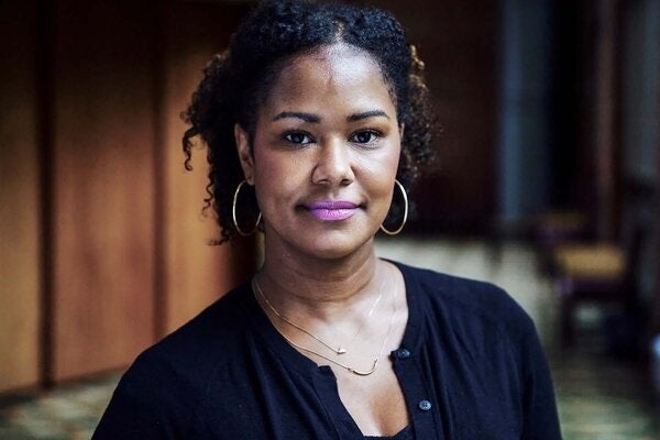 Georgetown University Prof. Soyica Diggs Colbert in a black shirt and hoop earrings, sits in the lobby of the Davis Performing Arts Center.